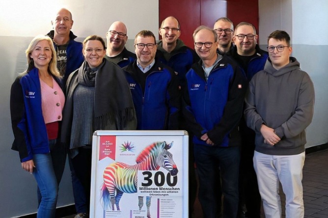 Gruppenbild Spendenaktion VW 2025 Gruppe von Menschen steht hinter einem Plakat mit einem bunten Zebra und der Zahl '300'